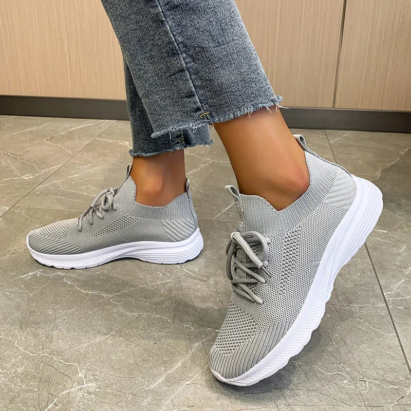 Women's low-top running shoes with mesh lining and Flyknit upper in creamy white, grey, or orange colours