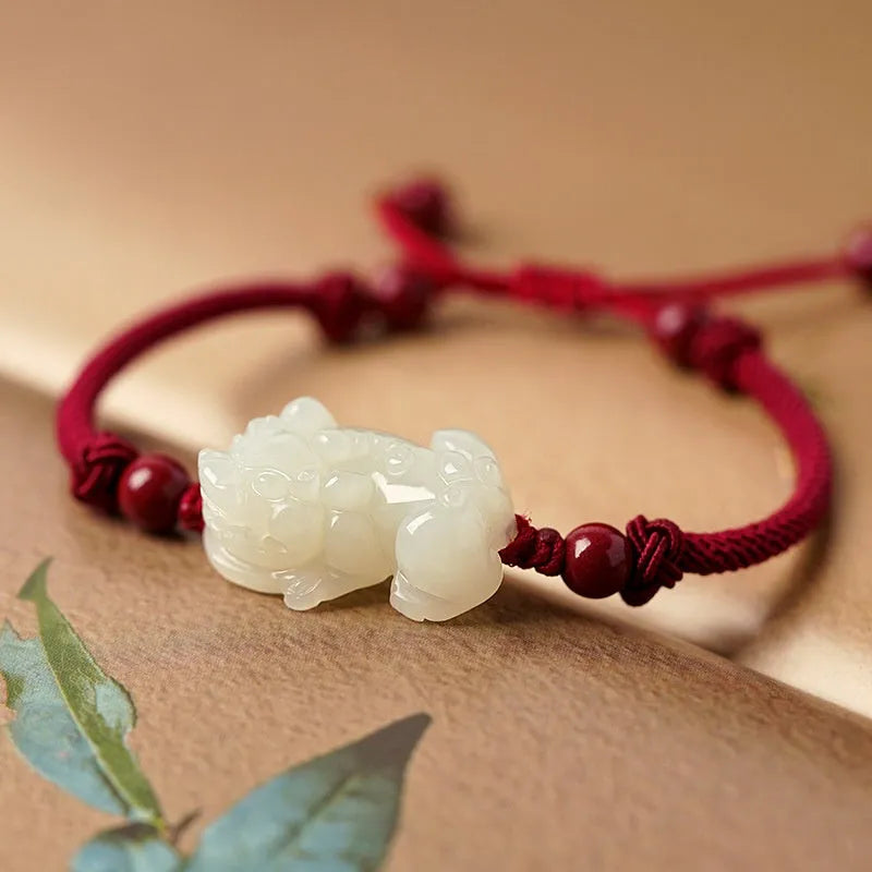 A Hetian jade bracelet with braided black and red rope in a Chinese style design.