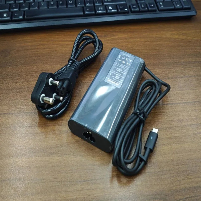 Black 65W Type-C laptop power adapter with multiple international power cords for UK US EU AU and ZA plugs.