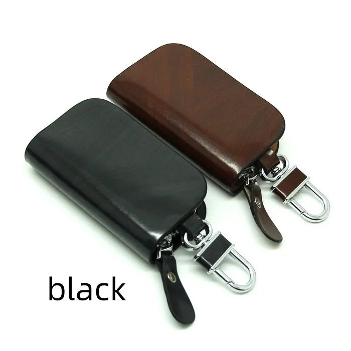 Black frosted leather car key case with zipper, next to a car key