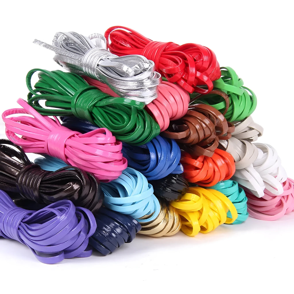 Spools of black, brown, and blue PU leather crafting cord in different widths on a craft table.