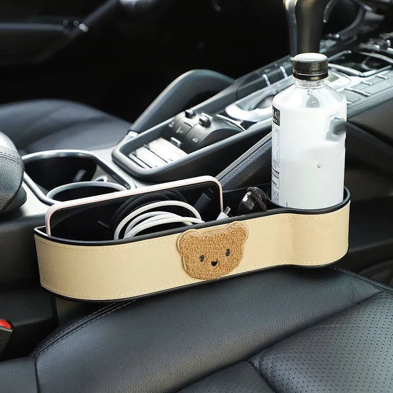 Leather car seat gap storage box with a cartoon bear design hanging between vehicle seats.