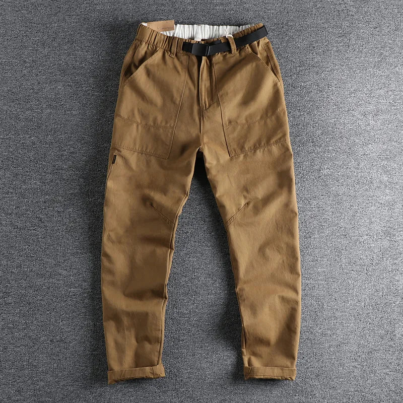 Men's khaki cotton work trousers with N buckle belt on a mid waist, showing three-dimensional cut.