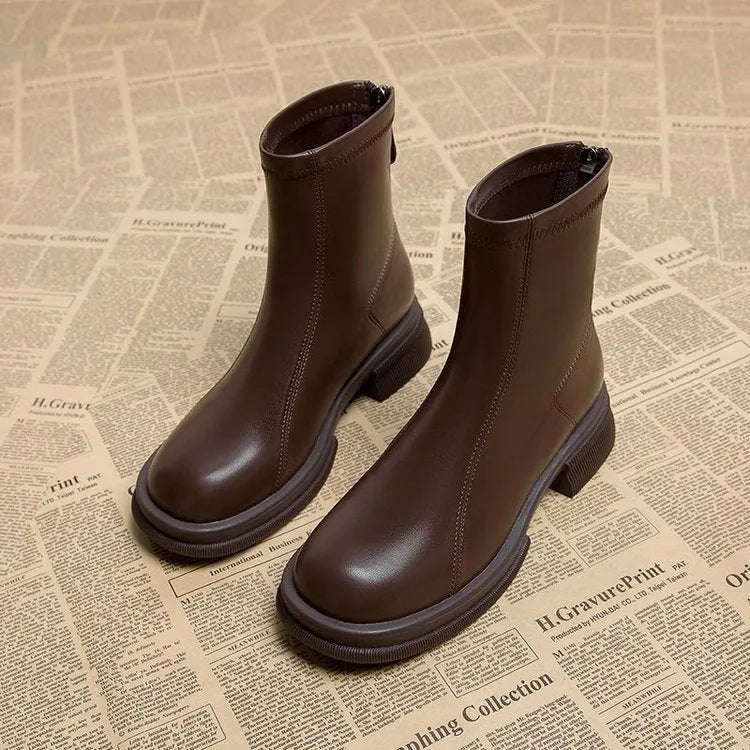 Women's black ankle boot with flat heel, round toe, and back zip on a plain background.