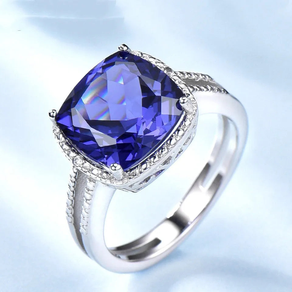 Blue Tanzanite stone set in a sterling silver women's ring on a grey background.