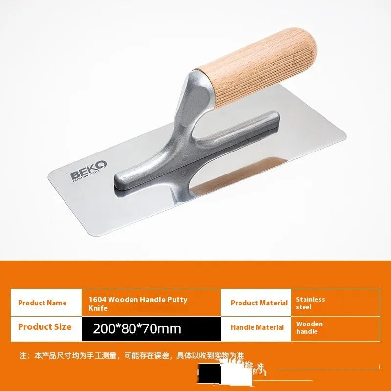 Three stainless steel putty scraper tools with wooden handles in different sizes on a workbench.