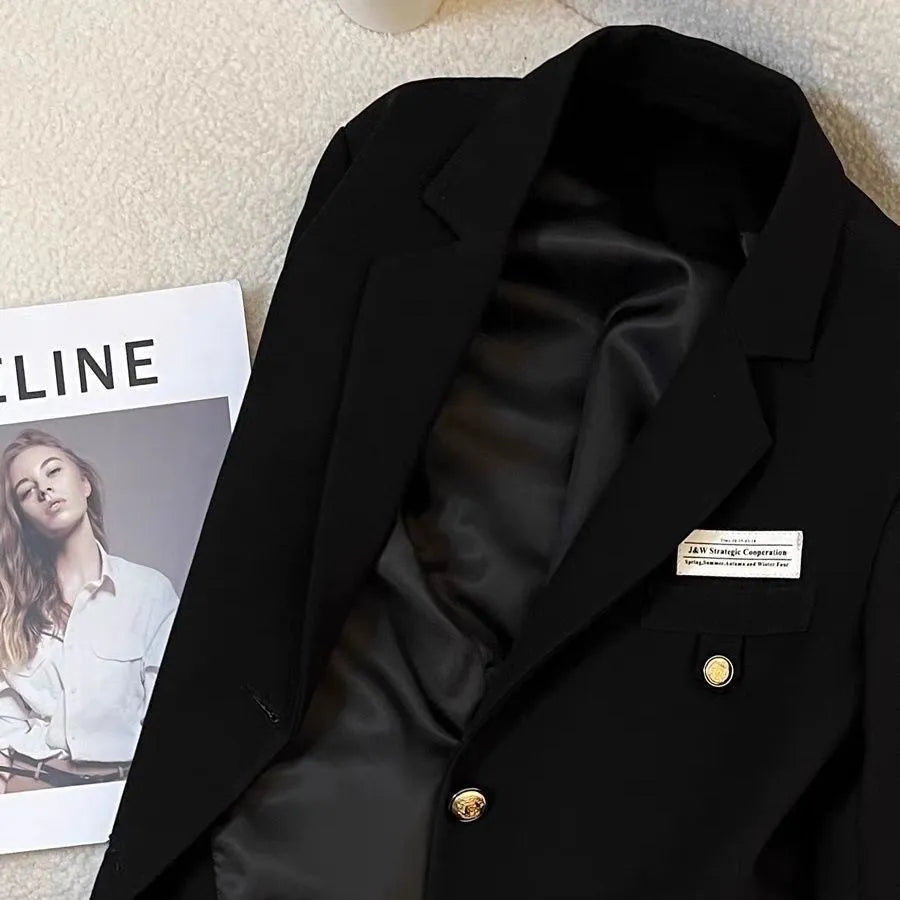Black loose-fit women's short suit coat with front pockets on a hanger.