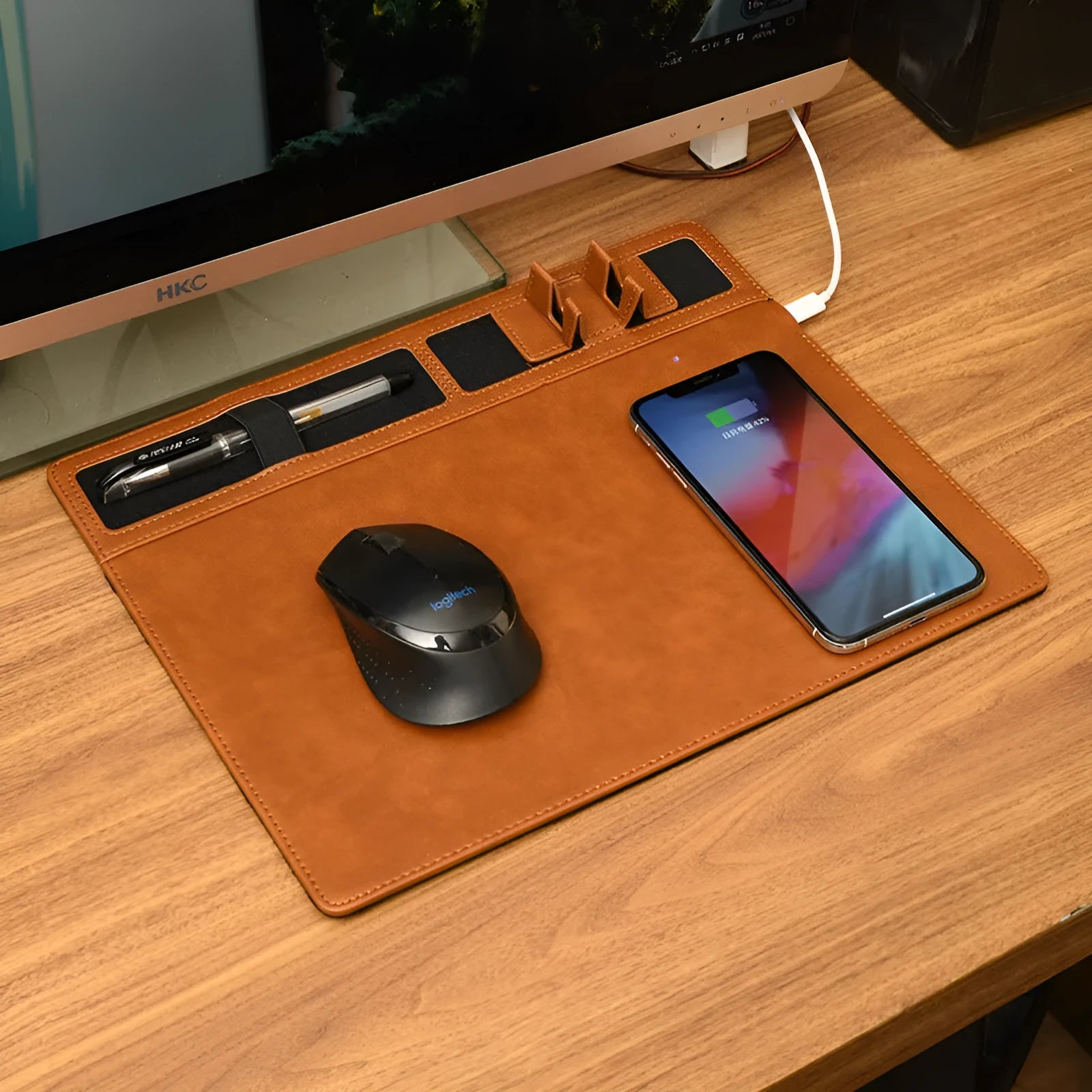 Pink PU leather wireless charging mouse pad with integrated phone holder on a desk.