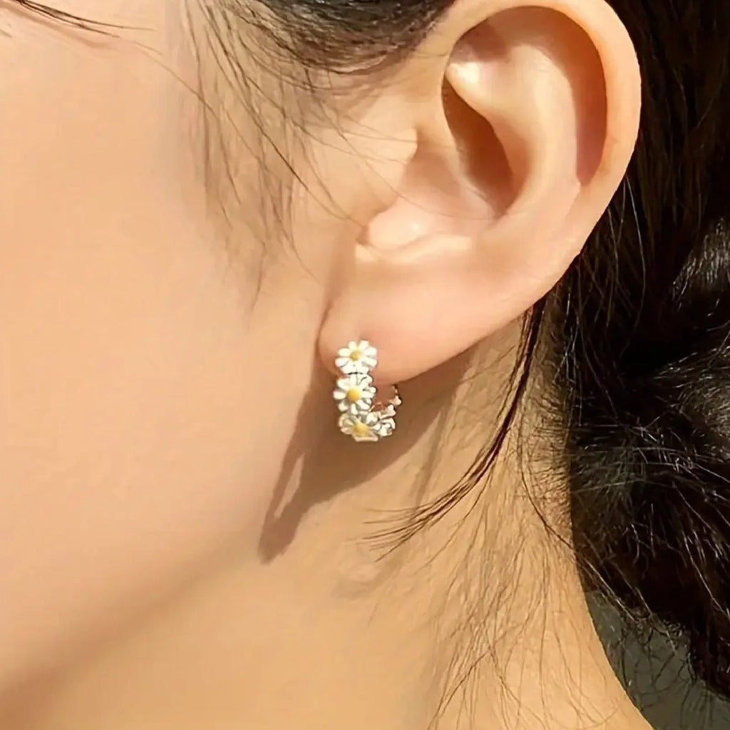White daisy flower ring style fashion earrings with inlaid gems on a model or plain background.