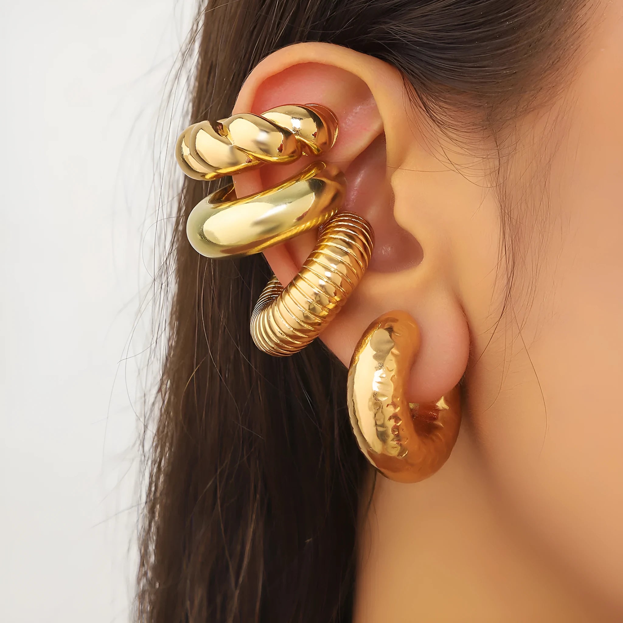 Set of four geometric clip-on earrings for women in gold or silver colour on a white background.