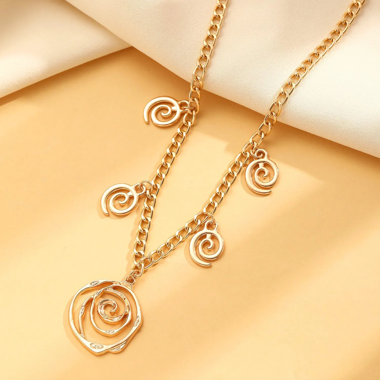 Women's spiral donut jewellery set showing matching necklace, bracelet and ear hooks in gold or silver electroplated alloy