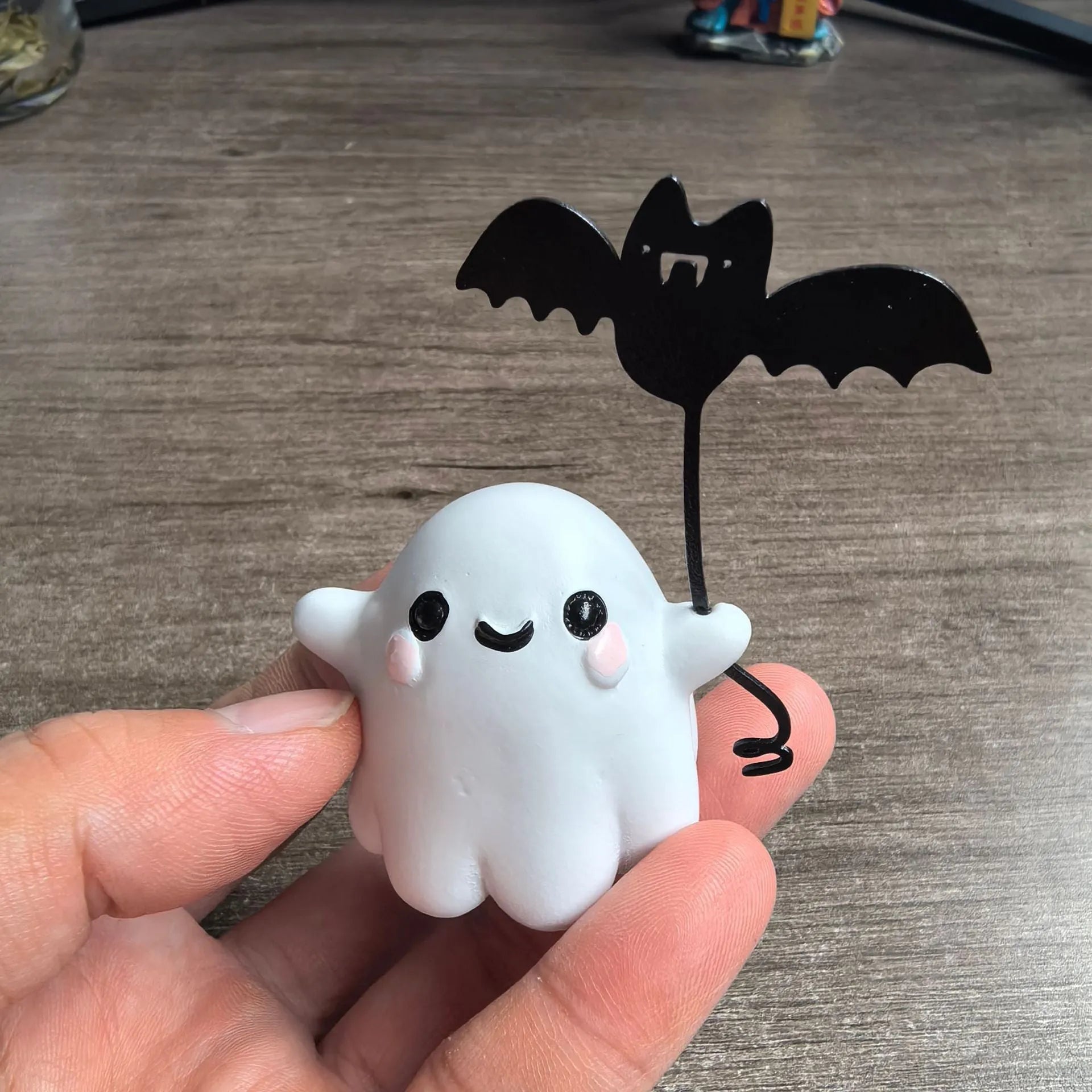 Miniature resin statue of a ghost walking a dog that is holding a bat, a Halloween decoration.