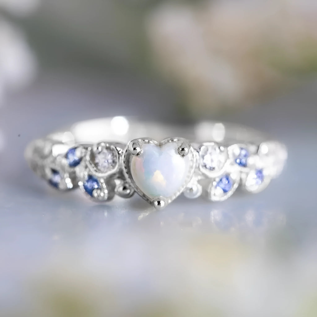 White heart-shaped women's alloy ring with floral and opal ocean design on finger