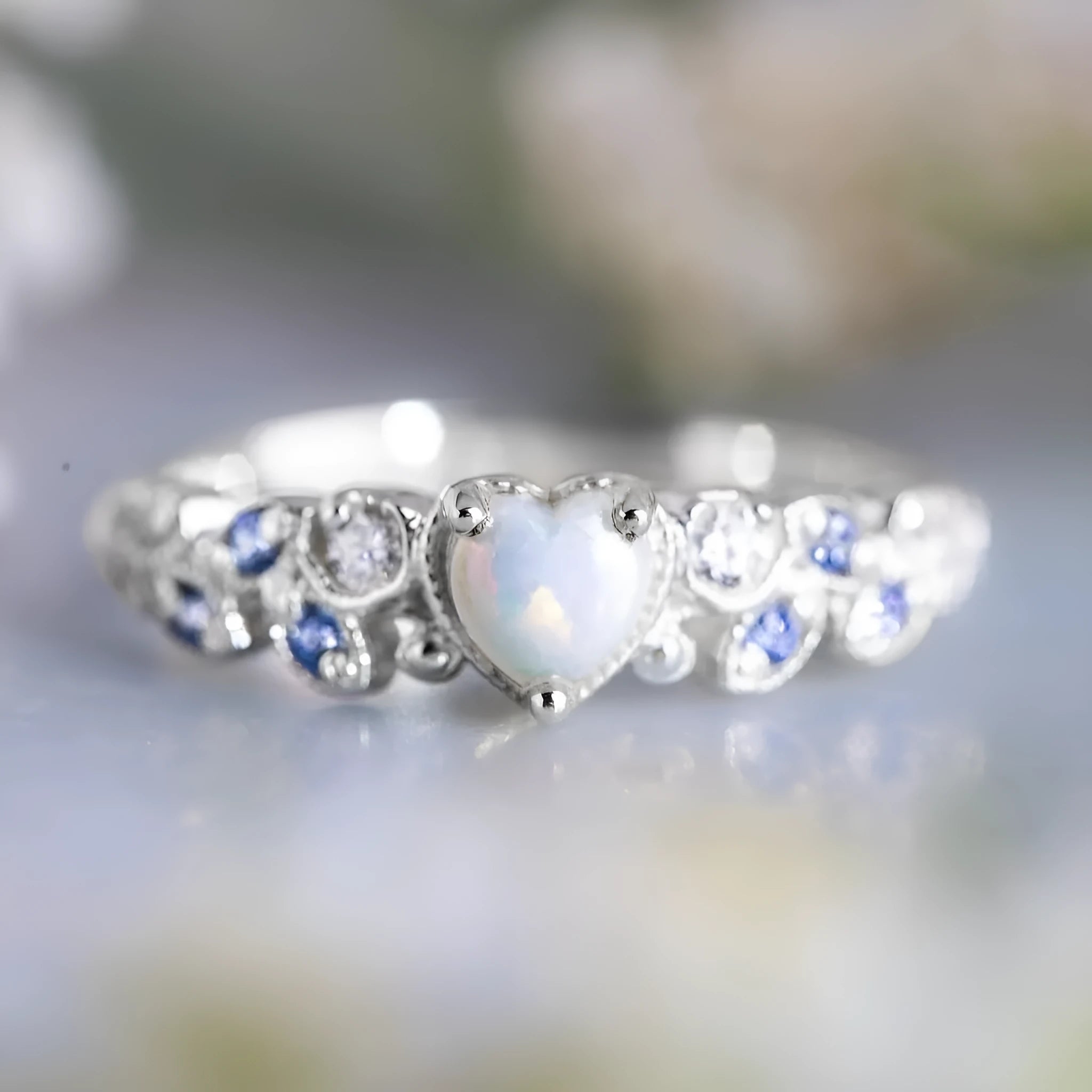 White heart-shaped women's alloy ring with floral and opal ocean design on finger