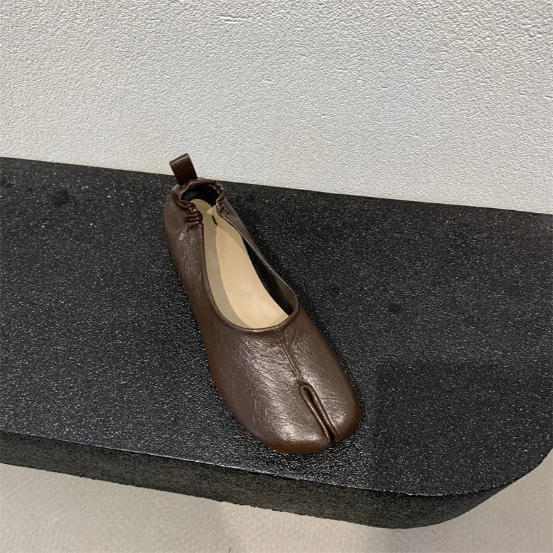 Women's black chunky heel pump with split toe and round toe design on a neutral background.