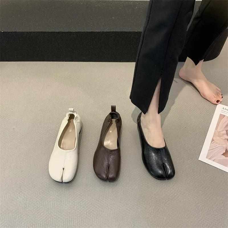 Women's black chunky heel pump with split toe and round toe design on a neutral background.