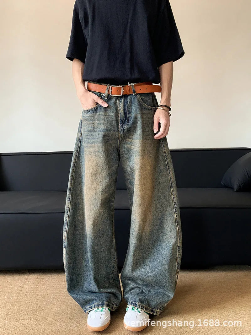Man wearing retro blue distressed denim jeans with a slim-fit wide-leg cut.