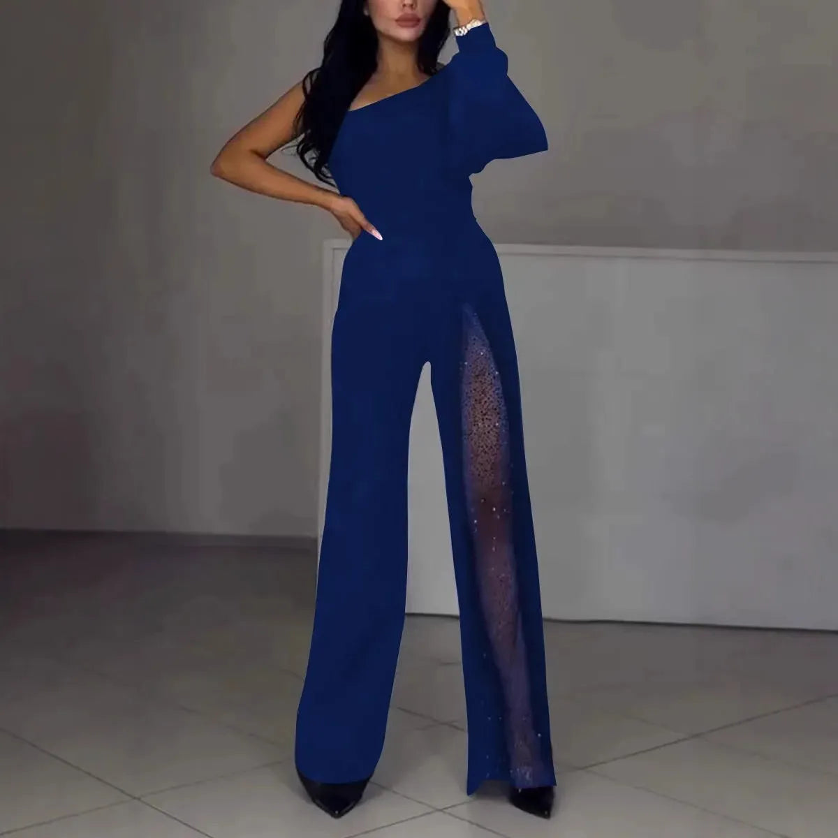 A woman wearing a black oblique shoulder jumpsuit with a high leg slit, made of polyester.