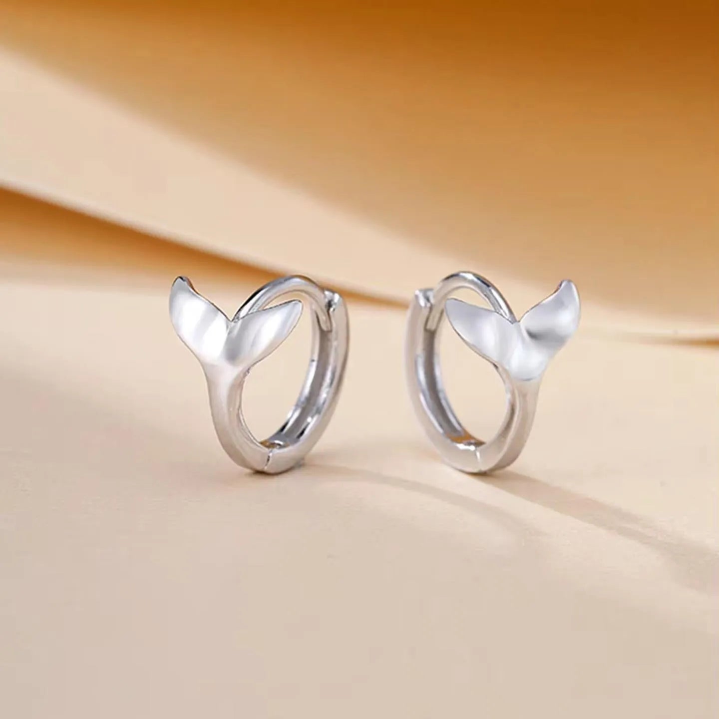 A pair of women's simple fishtail design earrings with an electroplated finish in white gold or yellow gold colour.