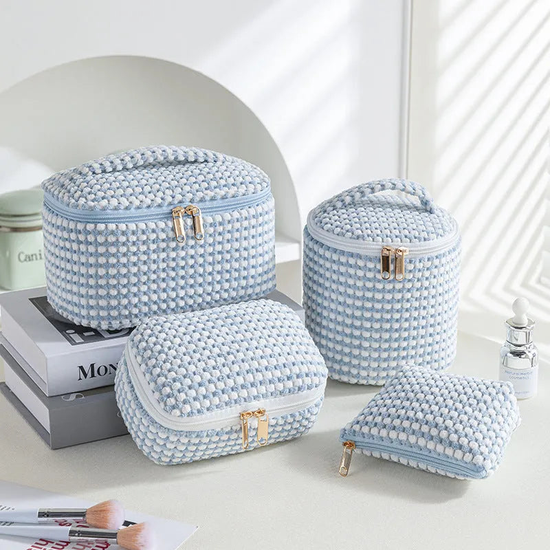 Four cube-shaped flannelette makeup bags in different colours for travel storage