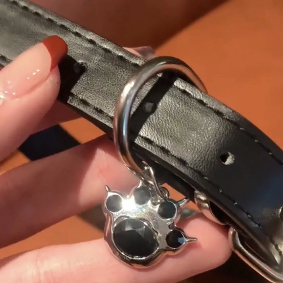 Black adjustable dog collar with bell showing three design options: LD leather, bone pattern, and cat's paw