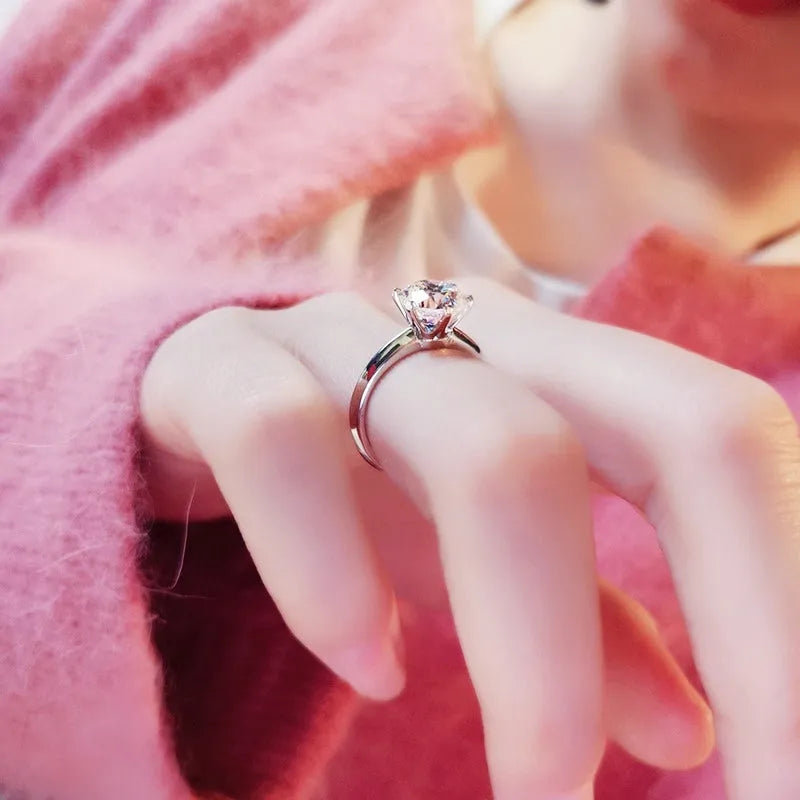 White gold plated geometric ring with a six-claw zircon setting on a hand.