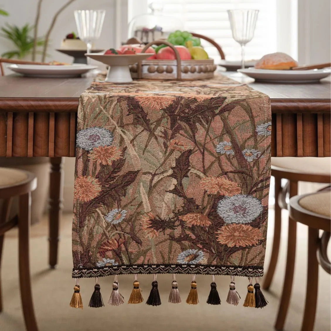 Beige jacquard table runner with floral pattern and long tassels laid flat on a table.