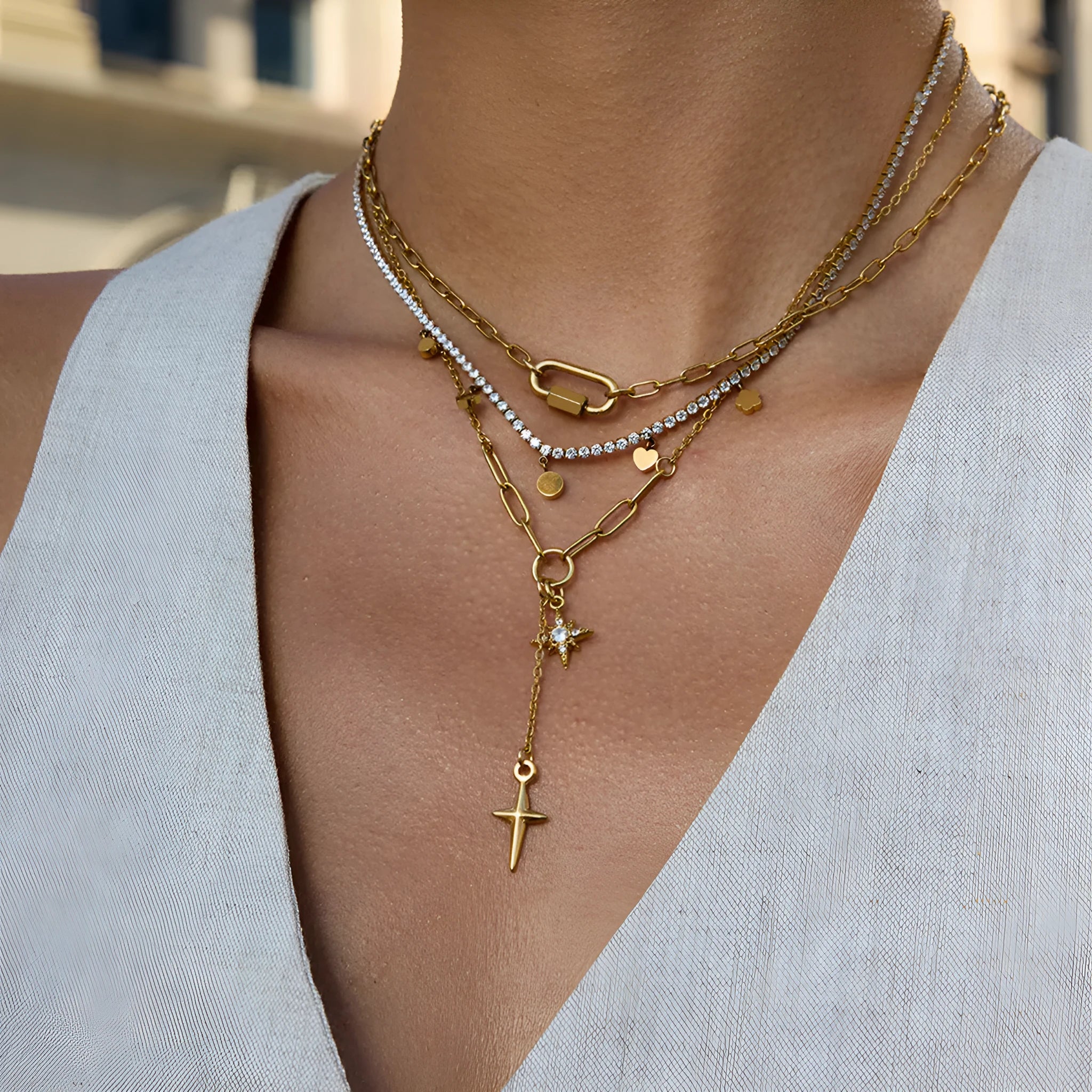 Close up of an 18K gold finish stainless steel necklace with white diamond eight-pointed stars pendant on a regular chain