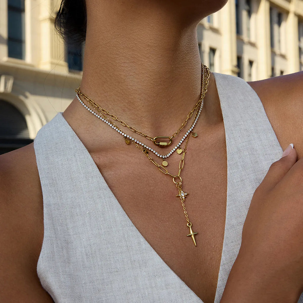 Close up of an 18K gold finish stainless steel necklace with white diamond eight-pointed stars pendant on a regular chain