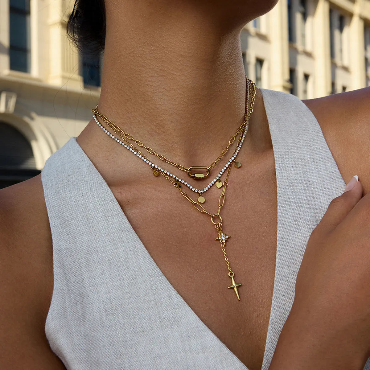 Close up of an 18K gold finish stainless steel necklace with white diamond eight-pointed stars pendant on a regular chain