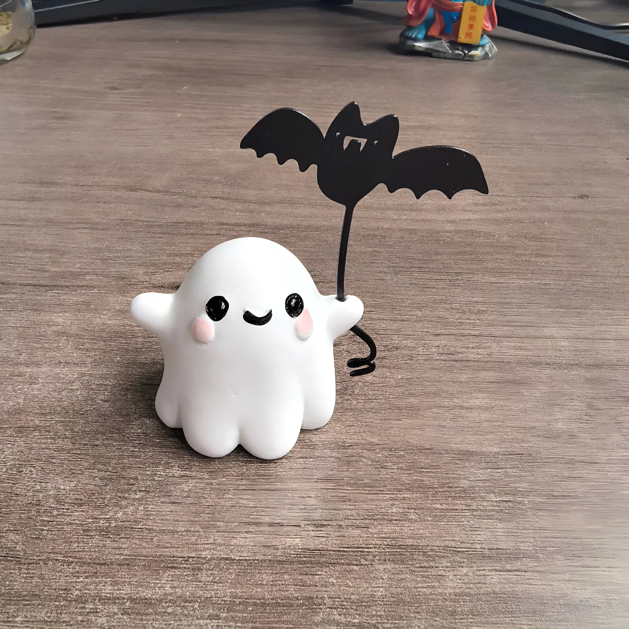 Miniature resin statue of a ghost walking a dog that is holding a bat, a Halloween decoration.