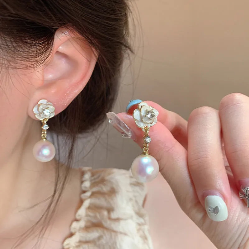 Close-up of women's camellia flower stud earrings in alloy with floral design.