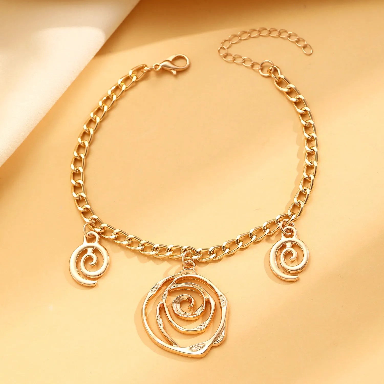Women's spiral donut jewellery set showing matching necklace, bracelet and ear hooks in gold or silver electroplated alloy