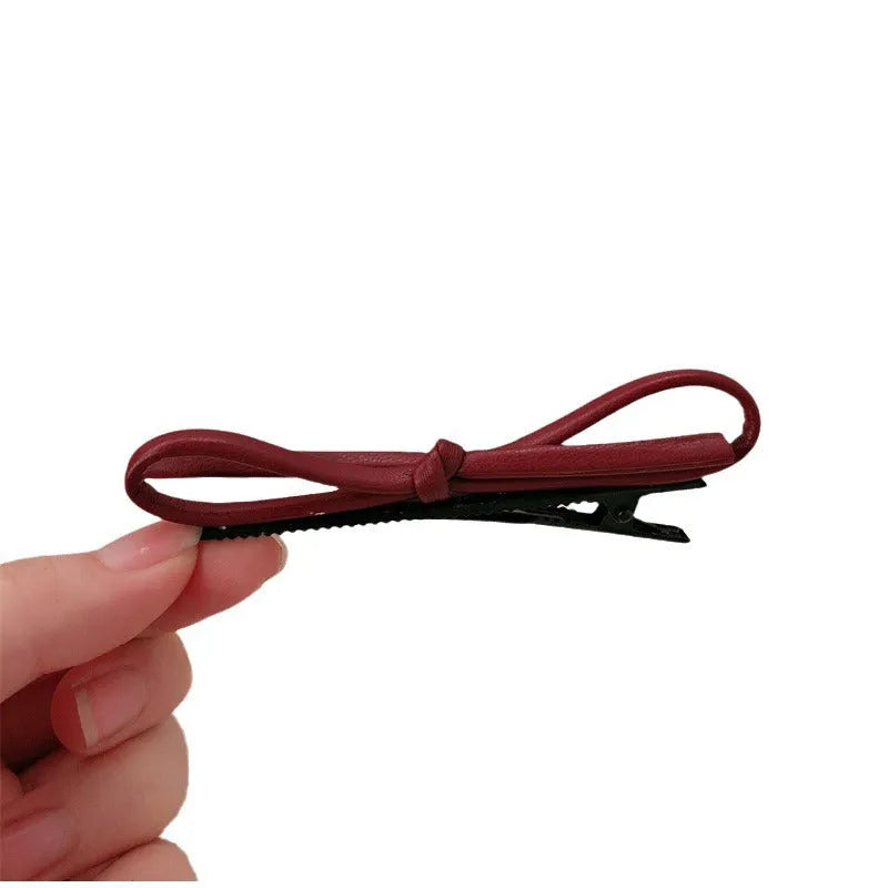 Wine red leather bow barrette hair clip on a white background.