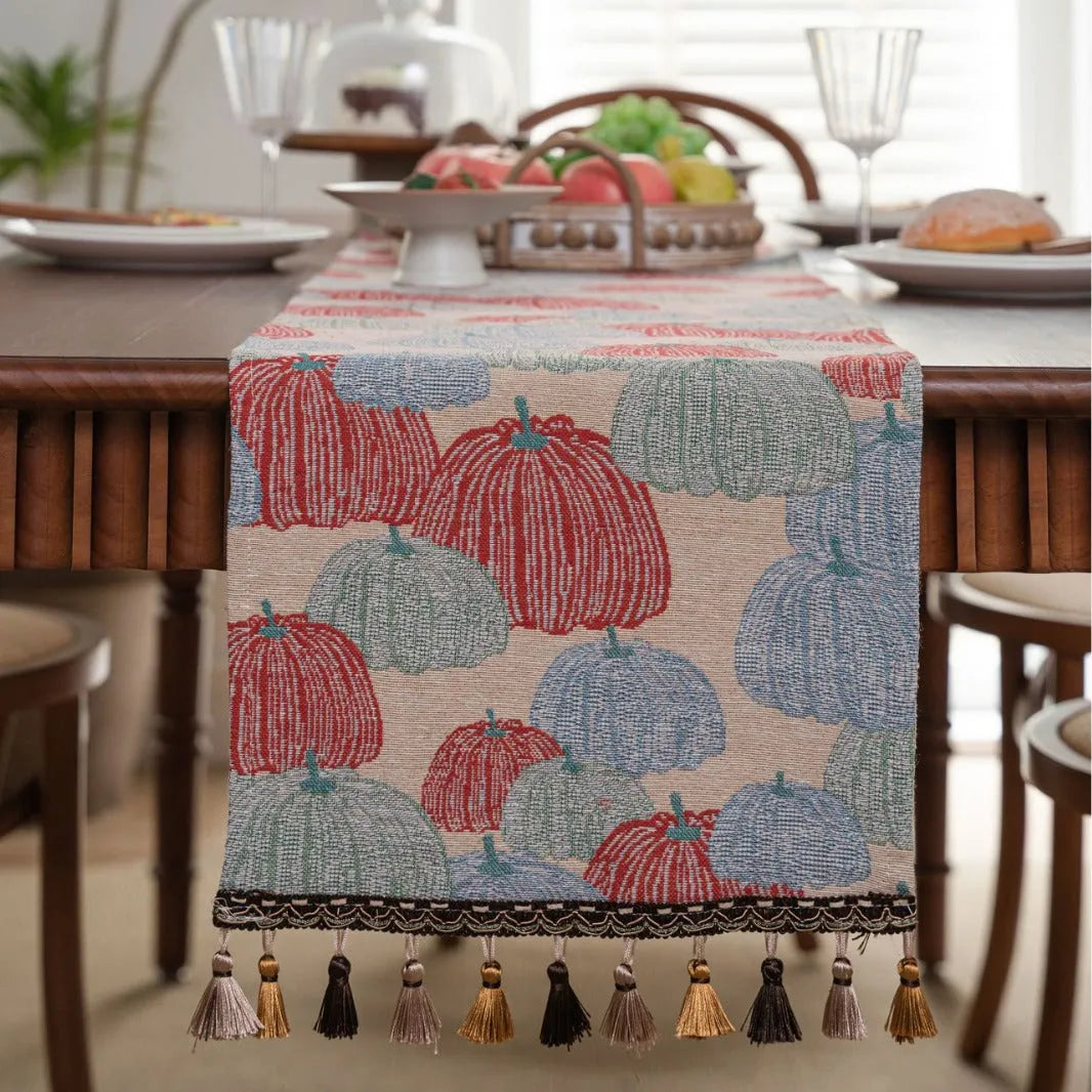 Beige jacquard table runner with floral pattern and long tassels laid flat on a table.