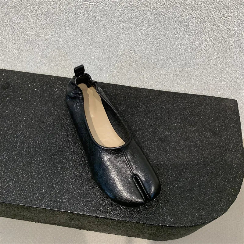 Women's black chunky heel pump with split toe and round toe design on a neutral background.