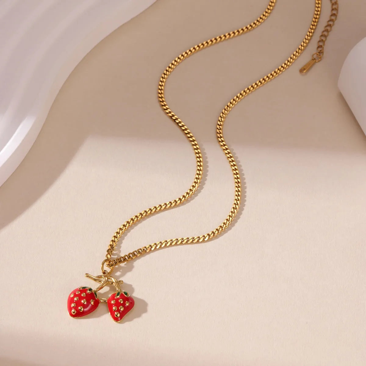 Close-up of a red stainless steel strawberry charm necklace on an alloy chain.