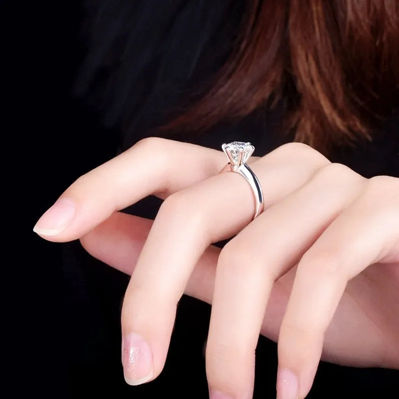 White gold plated geometric ring with a six-claw zircon setting on a hand.