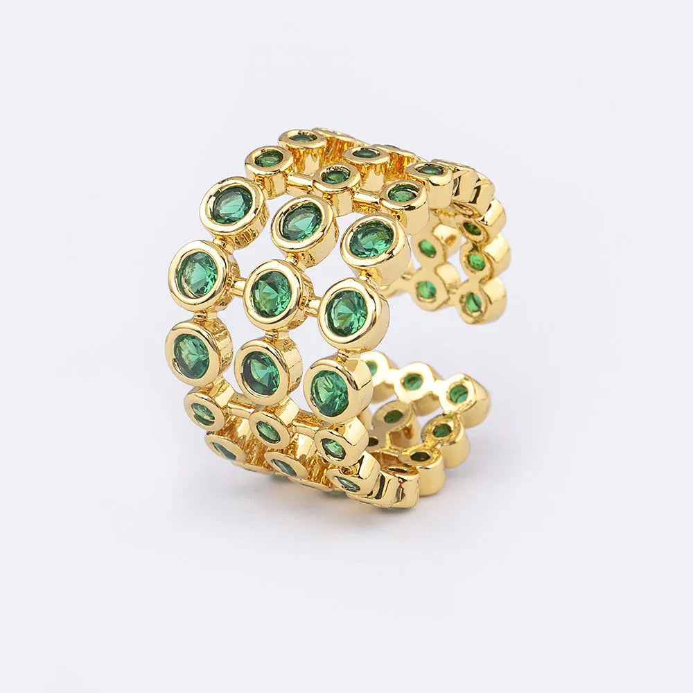 A wide, gold-coloured ring with a three-layer design and a large green cubic zirconia stone on a copper base.