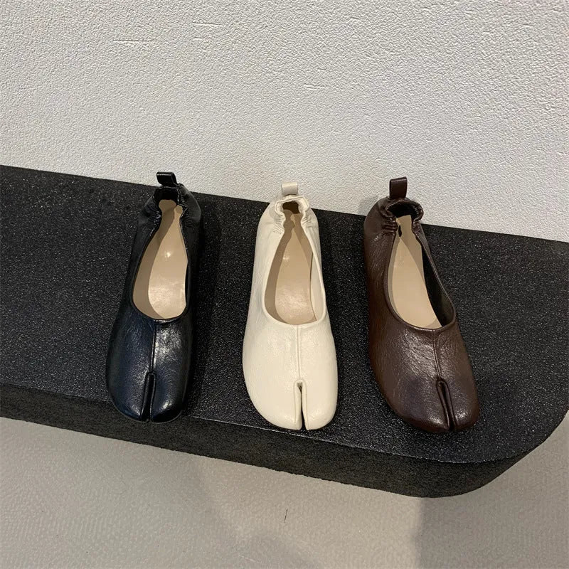 Women's black chunky heel pump with split toe and round toe design on a neutral background.
