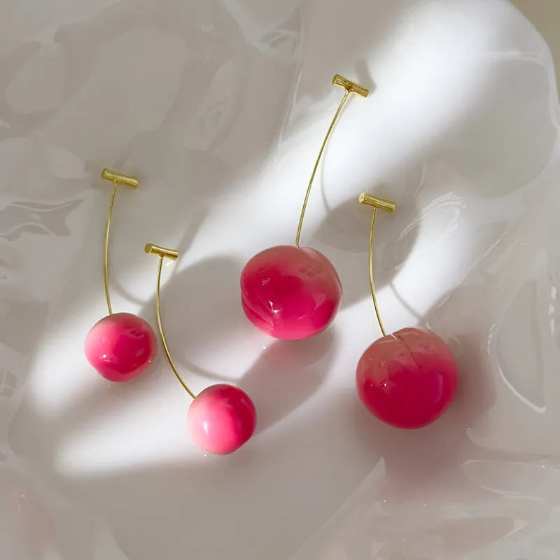A pair of women's earrings with a clear acrylic peach charm on copper posts