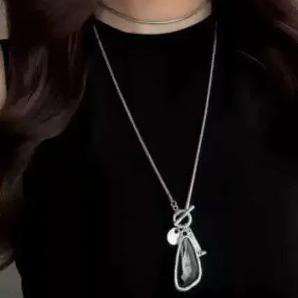 Long alloy necklace with geometric pendant on a snake bones chain, shown in blue water drop colour.