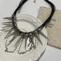 Close-up of a women's casual necklace with leather cord, electroplated round beads, and point rivets in a winding tassel design.