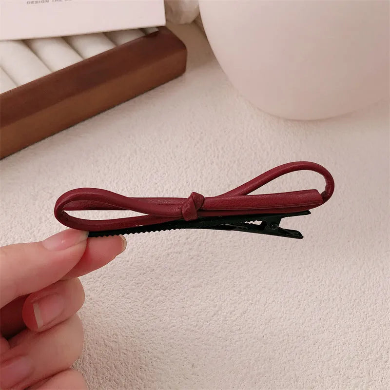 Wine red leather bow barrette hair clip on a white background.