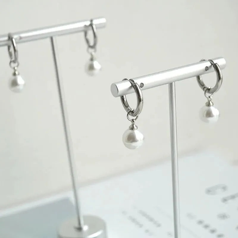 A pair of women's geometric alloy earrings with a round pearl and titanium steel posts.