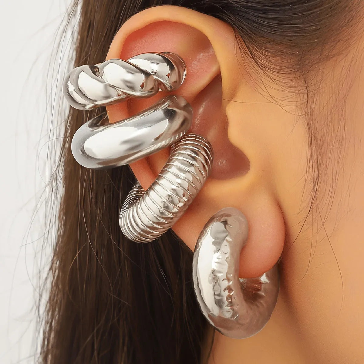 Set of four geometric clip-on earrings for women in gold or silver colour on a white background.