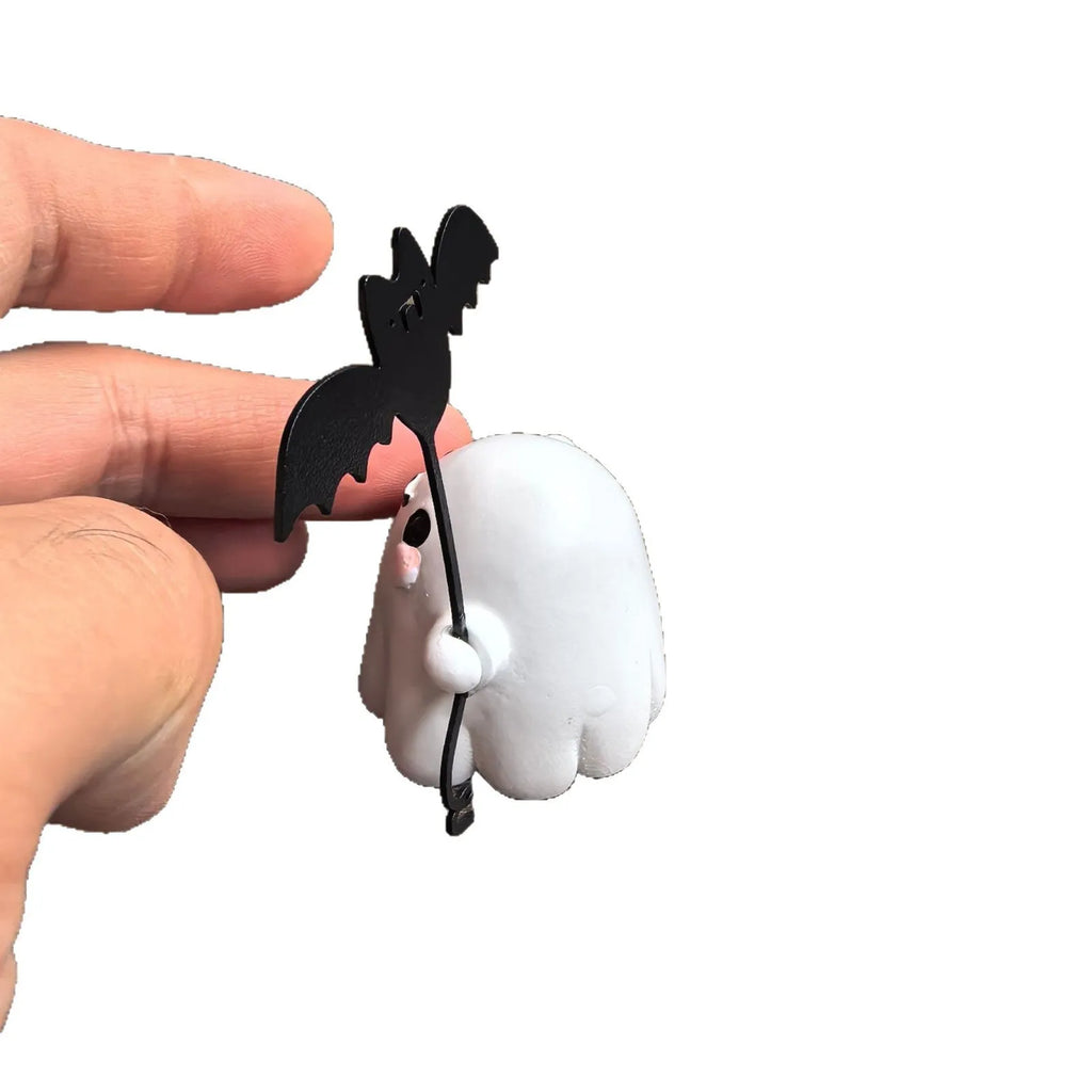 Miniature resin statue of a ghost walking a dog that is holding a bat, a Halloween decoration.