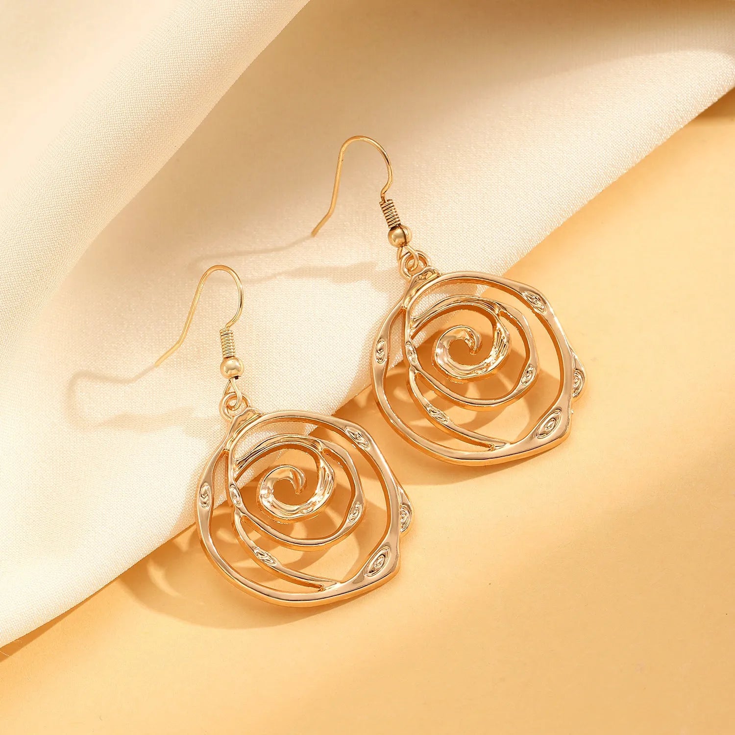 Women's spiral donut jewellery set showing matching necklace, bracelet and ear hooks in gold or silver electroplated alloy