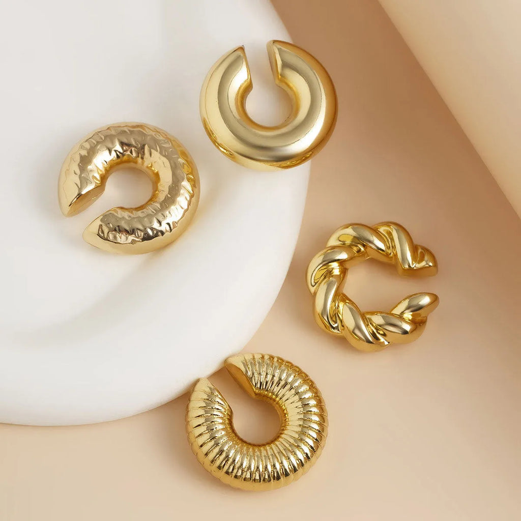 Set of four geometric clip-on earrings for women in gold or silver colour on a white background.
