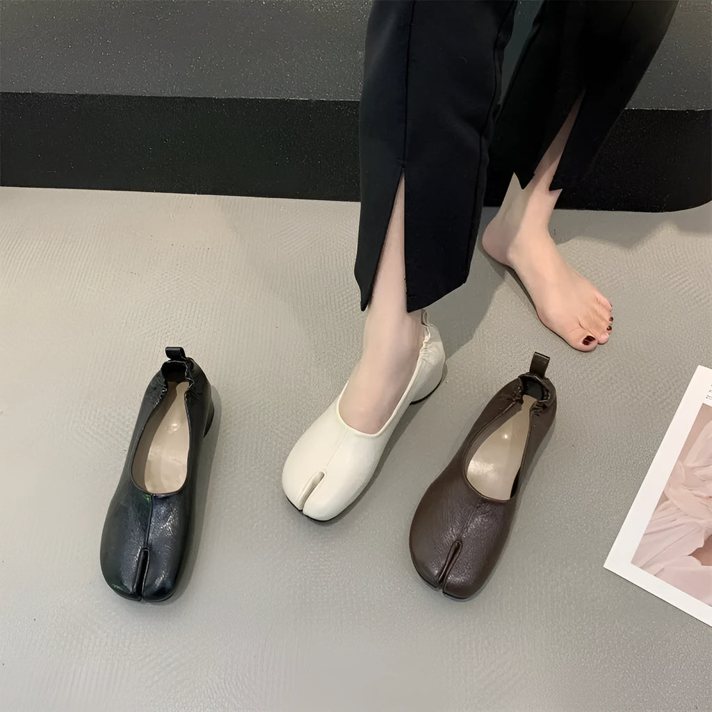 Women's black chunky heel pump with split toe and round toe design on a neutral background.